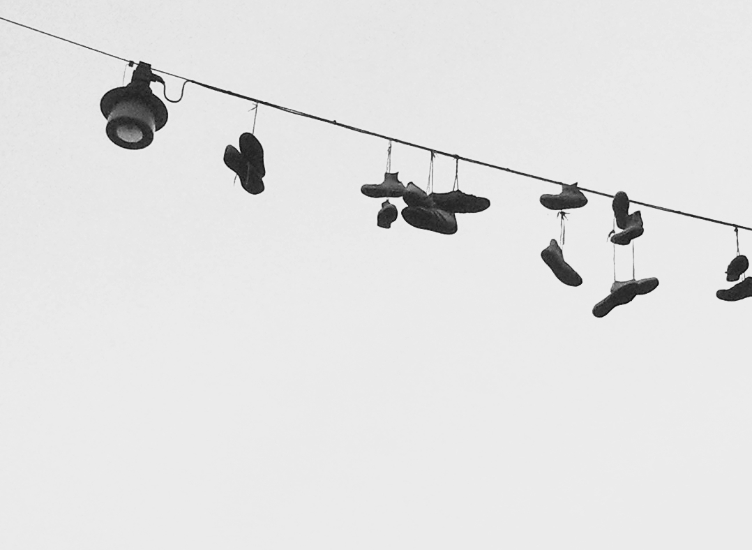 Schuhe baumeln am Kabel einer Straßenlaterne über einer Kreuzung